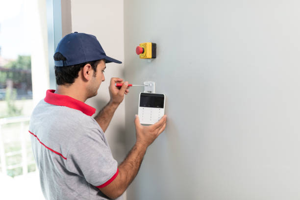 técnico de alarmas instalando teclado de control en pared